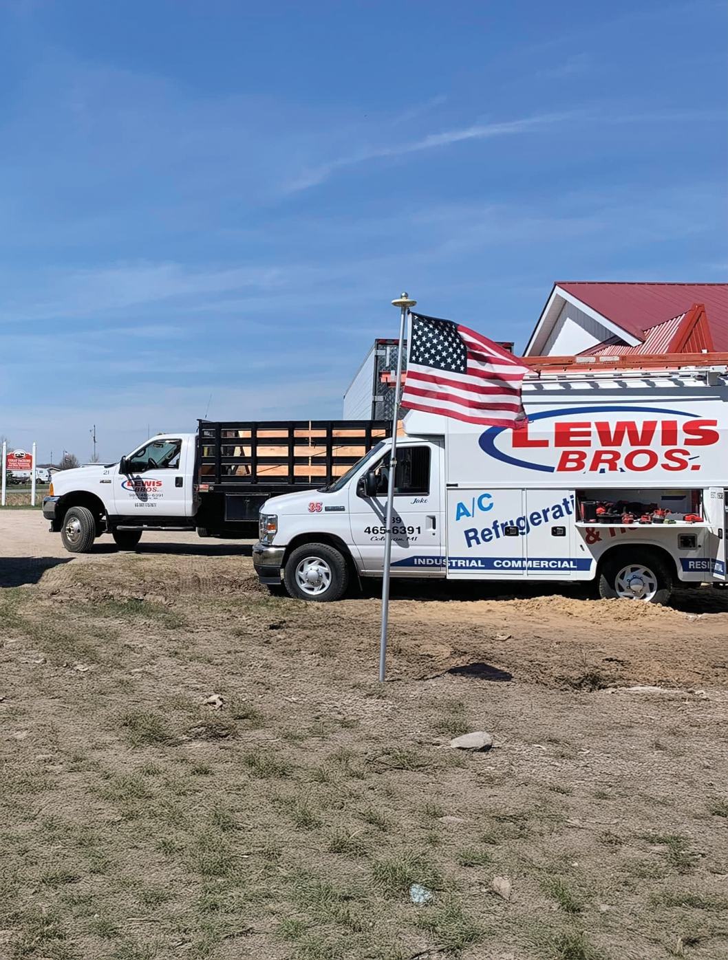 Lewis Bros Inc service trucks parked beside an American flag in Coleman, Michigan