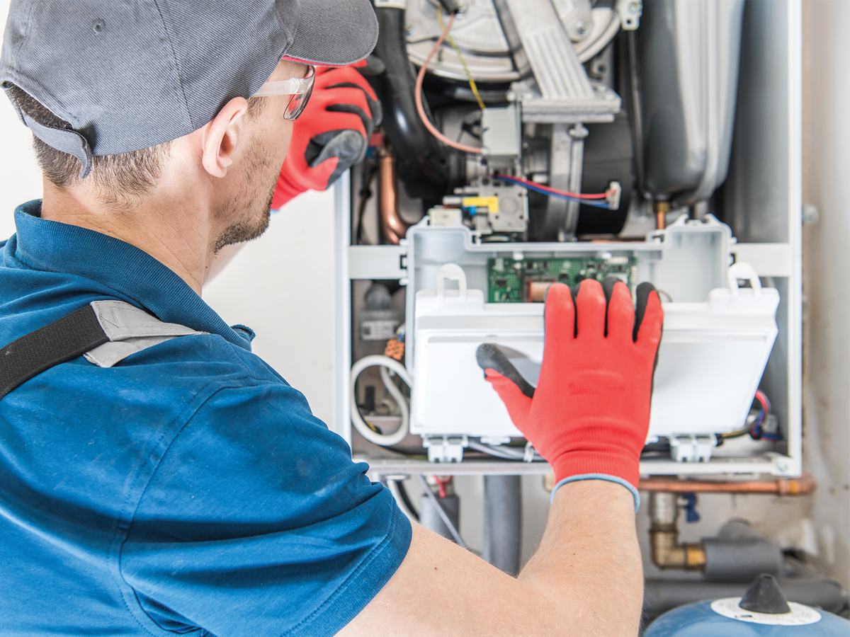 An HVAC technician repairing a furnace control board