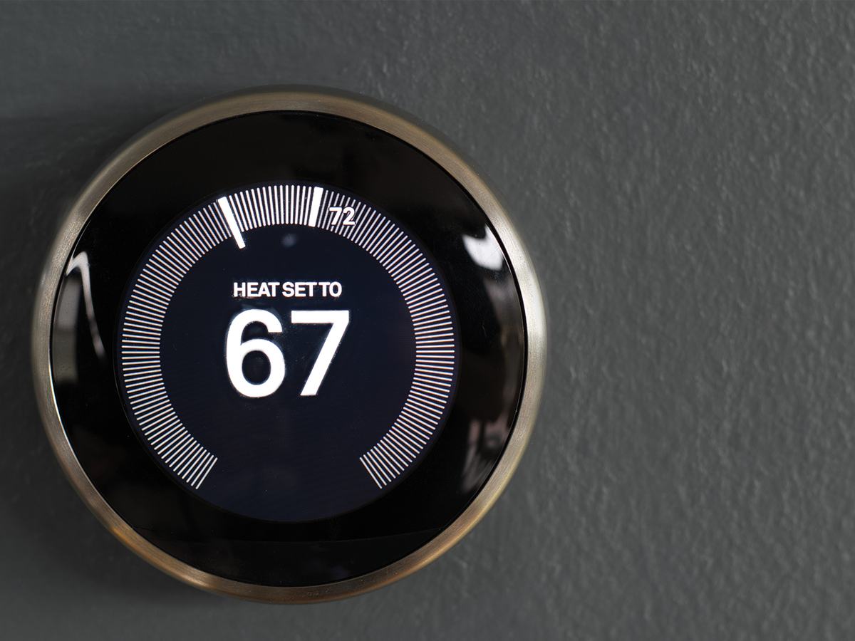 A smart thermostat on a wall, set to heat to 67 degrees